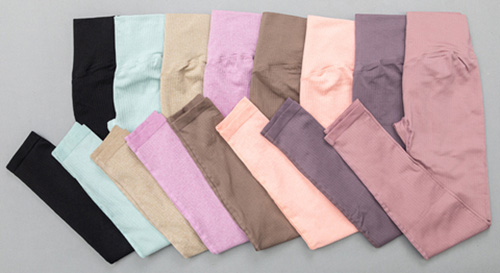 A flat lay of multiple pairs of high-waisted women's leggings in various colors, including black, mint green, beige, pink, brown, peach, and mauve, neatly arranged on a gray surface.