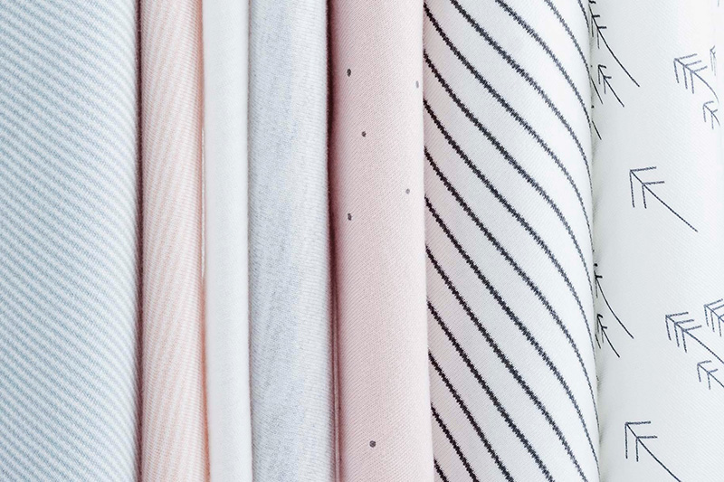 Soft pastel fabrics with stripes, dots, and arrow prints neatly aligned