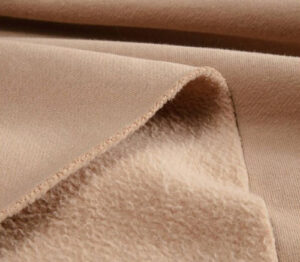 Close-up of beige fleece fabric showing soft brushed interior texture and smooth exterior surface for warm clothing