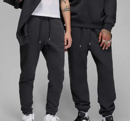Two men wearing black jogger sweatpants with drawstring waists and tapered ankles.