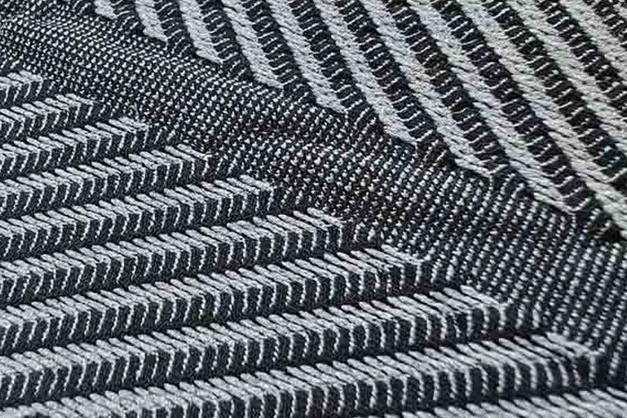 Close-up of black and white fabric with a diagonal herringbone pattern, showing the woven texture in detail.