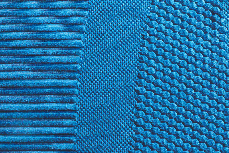 Close-up of blue fabric showing three distinct knit textures side by side