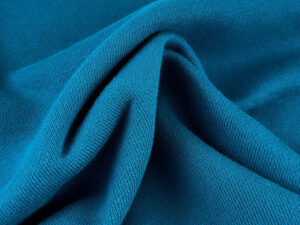 Close-up of blue French terry cotton fabric with soft knit texture and folded drape for comfortable apparel manufacturing