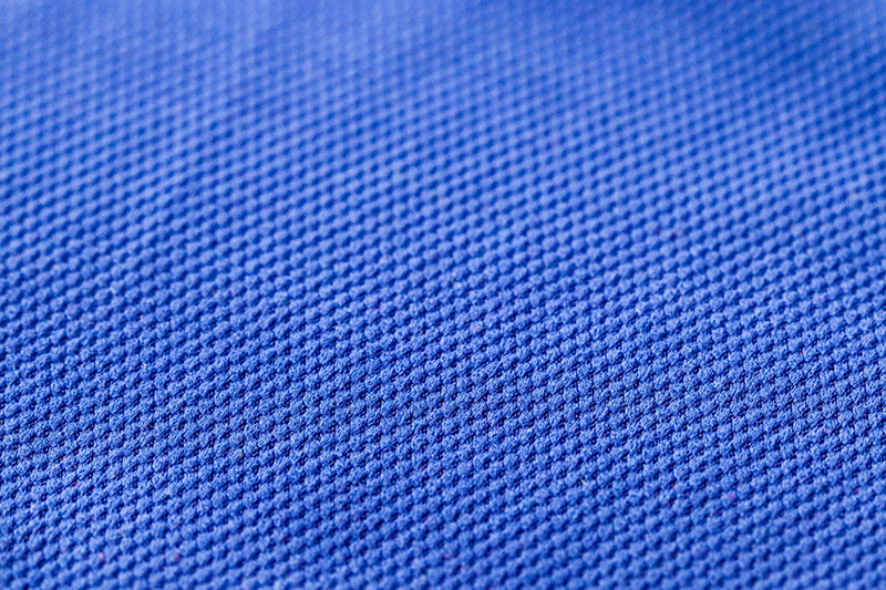 Close-up of blue piqué fabric texture with small breathable knit pattern.