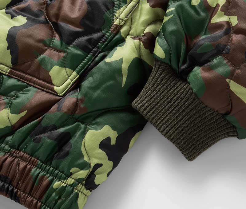Close-up of a green and brown camouflage quilted jacket sleeve with elastic cuff.