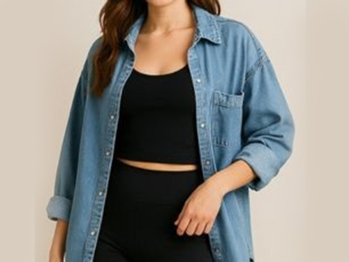 Woman wearing a black crop top paired with black high-waisted leggings, layered under an oversized light blue denim button-up shirt with rolled-up sleeves.