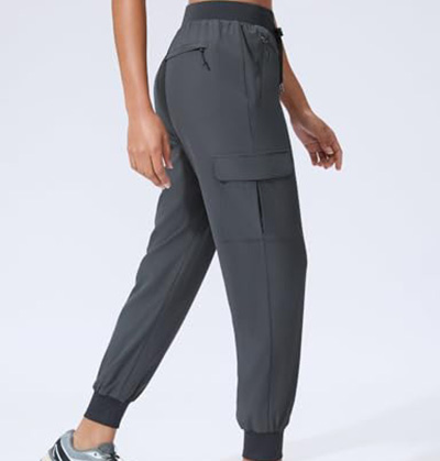 Woman wearing charcoal gray cargo jogger pants with ankle cuffs and side flap pocket.