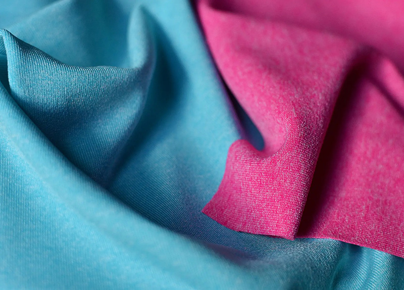 A close-up view of two pieces of fabric, one turquoise blue and one bright pink, with soft folds and a slightly textured surface.