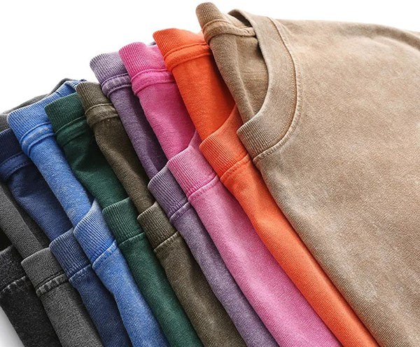 Folded washed T-shirts in assorted colors including beige, orange, pink, purple, green, and blue.