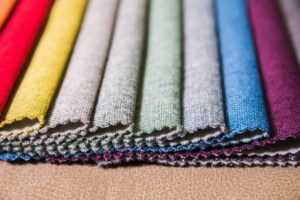 Stacked colorful jersey fabric swatches displaying different knit textures and vibrant shades for apparel and textile material selection