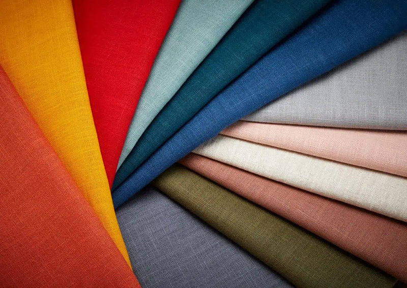 Assorted colorful linen fabric samples arranged in vibrant folded textile display