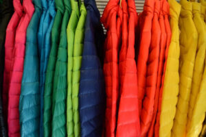 Bright multicolor puffer jackets hanging together in vibrant rainbow-inspired winter fashion display