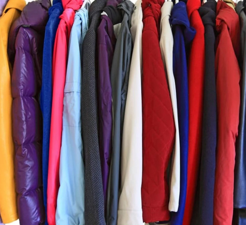 Rack of colorful winter jackets and coats hanging closely together in bright mixed tones.