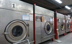 Row of industrial washing machines used in commercial garment laundry facility