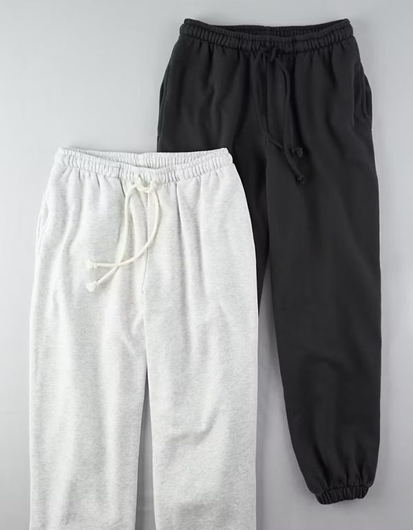 White and black sweatpants shown side by side with elastic waistbands and relaxed fit.