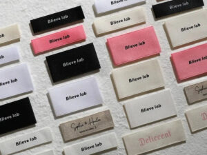 Assorted woven clothing labels in black, white, and pink branding designs