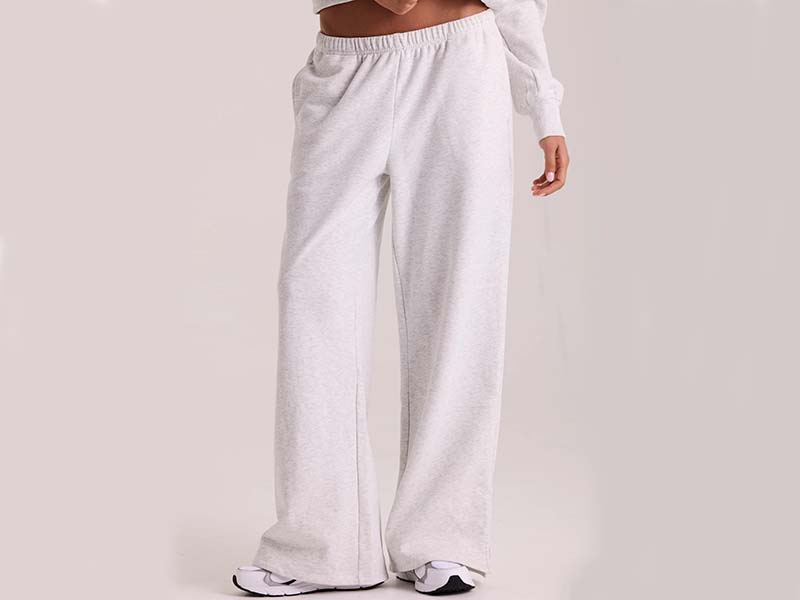 Woman wearing light grey wide-leg lounge pants with elastic waistband and white sneakers.