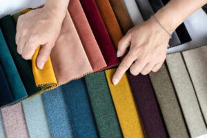 Hands comparing colorful fabric swatches in different textures and shades for textile and fashion material selection