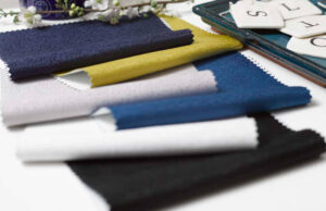 Folded textile fabric swatches in multiple colors including navy, yellow, gray, white, and black for fashion and design selection