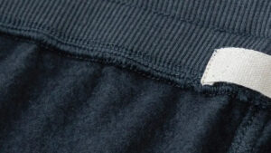 Detailed close-up of black fleece fabric showing soft brushed texture and stitched waistband edge