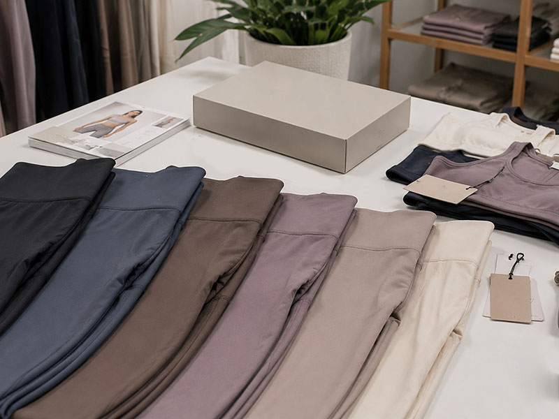 olded women’s leggings in neutral shades from black to cream, neatly displayed on a table with matching tops and packaging box