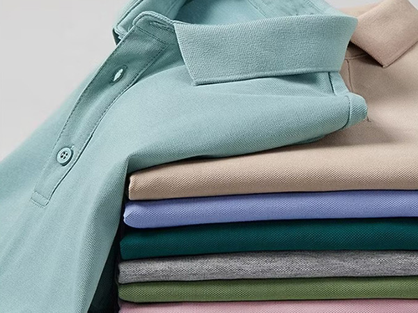 Stack of folded piqué polo shirts in mint, beige, blue, teal, gray, green, and pink.