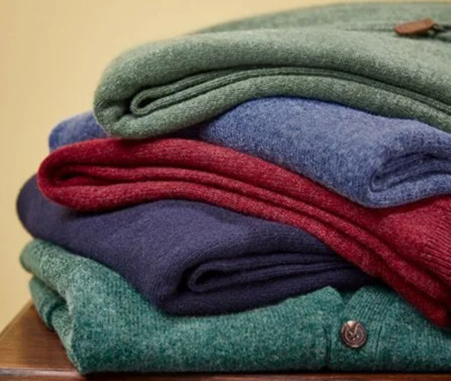 Stack of colorful folded wool sweaters with soft knit texture and warm fabric