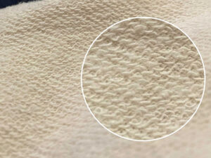 Close-up of cream French terry fabric showing soft looped inner texture and detailed knit surface for comfortable sweatshirt material