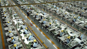 Large garment factory with workers operating sewing machines in textile production line