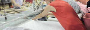 Textile worker ironing fabric pieces in a busy garment production workshop setting