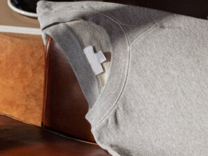 Close-up of heather grey crewneck sweatshirt with soft fleece lining and ribbed collar detail on leather chair