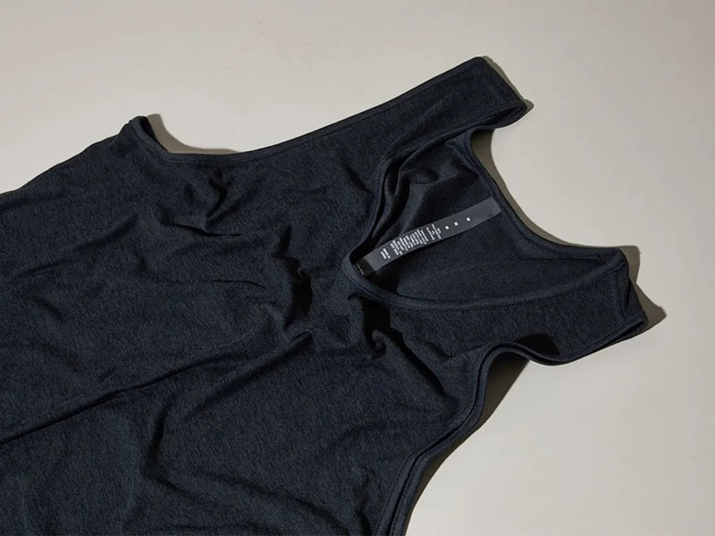 Black sleeveless tank top laid flat, showing soft fabric and simple scoop-neck design.