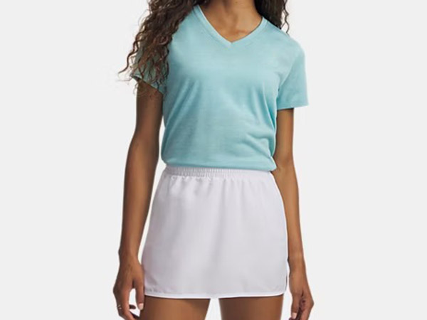 A person standing, wearing a light blue short-sleeve V-neck t-shirt tucked into a white athletic skort.