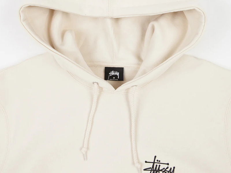 Close-up of cream pullover hoodie with drawstrings, soft fleece interior, and minimalist streetwear design details