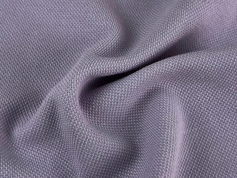 Close-up view of a lavender-colored knit fabric, showing its textured weave and gentle folds.
