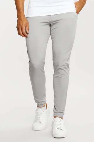 Men’s light gray slim-fit jogger pants with tapered ankles and white sneakers.