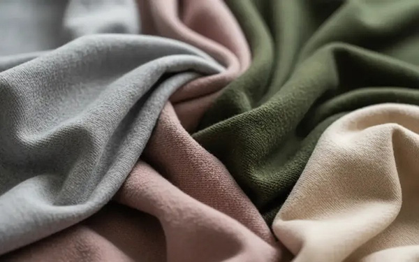 Soft draped fabrics in gray, blush pink, olive green, and beige tones.