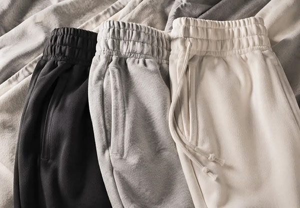 Three jogger sweatpants in black, gray, and cream with elastic waistbands and pockets.