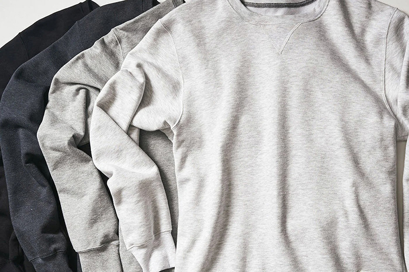 Three crewneck sweatshirts layered in black, charcoal, and light gray neutral tones.