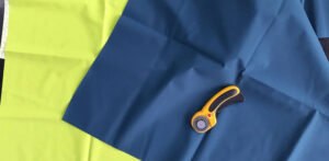Blue and green nylon fabric sheets with rotary cutter for textile production work