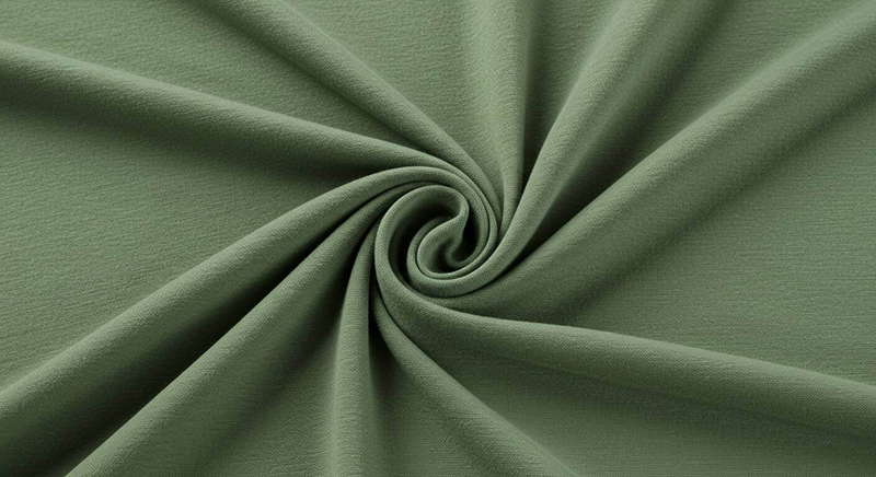 A single piece of olive green bamboo fabric arranged in a spiral, highlighting its smooth texture and soft drape.
