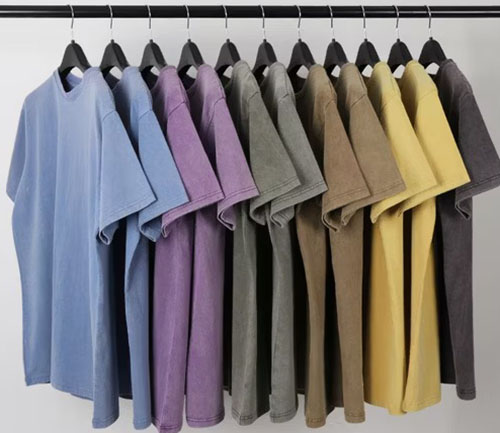 Colorful oversized T-shirts hanging on a rack in pastel and earthy tones.