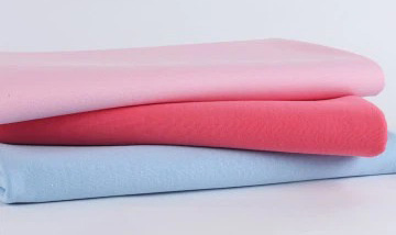 Three folded fleece fabrics in pastel pink, coral, and light blue tones.