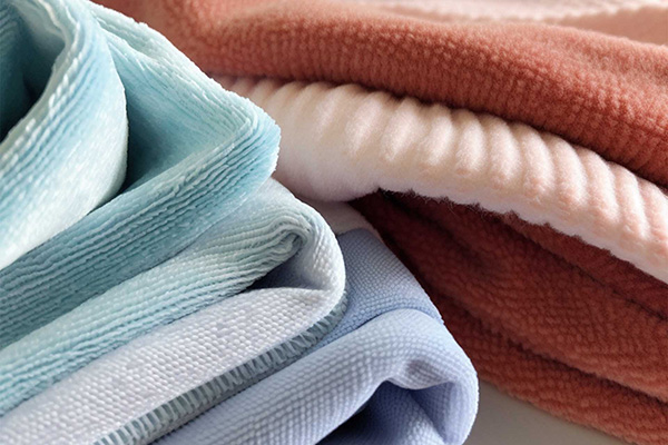 Soft plush fabrics in pastel blue, blush pink, cream, and rust tones layered together.