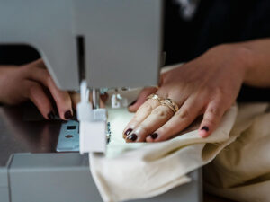 Close-up of hands guiding fabric through sewing machine during garment manufacturing process