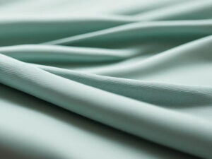 Soft mint green performance fabric with smooth texture and elegant flowing folds for activewear and apparel design