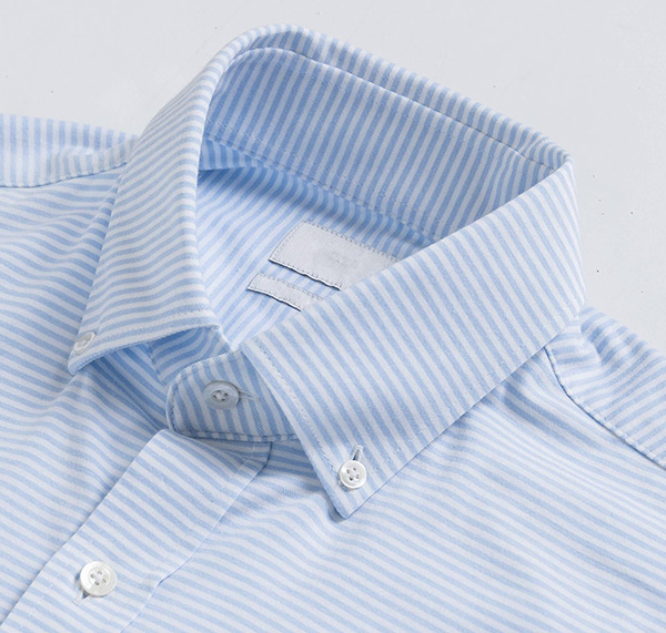 Close-up of light blue and white striped button-down shirt collar with classic tailoring details.