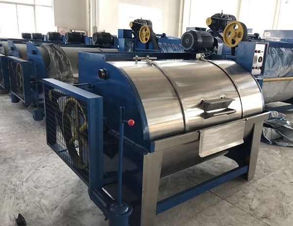 Industrial textile machine with stainless drum units lined up on a factory floor.
