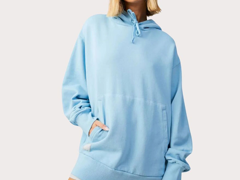 Woman wearing oversized light blue hoodie with front pocket and relaxed casual streetwear fit