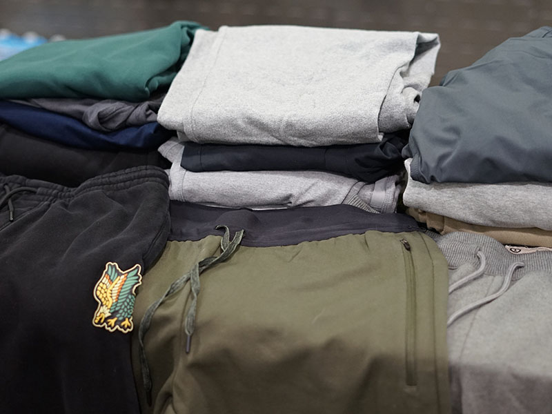 Stacked activewear clothing and joggers in neutral tones displayed on a table